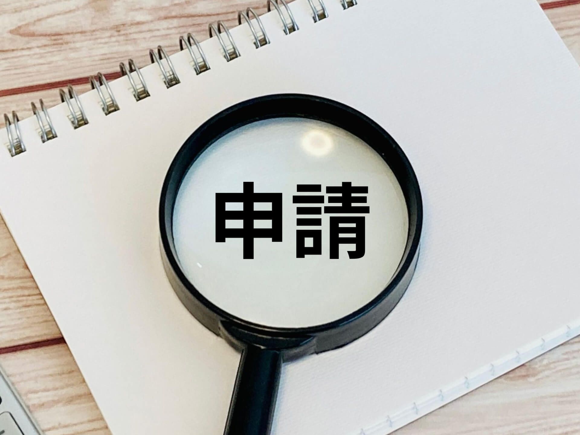ノートと虫眼鏡で申請を確認